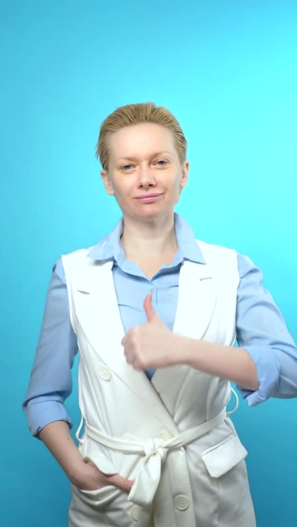 Tiro vertical. mulher loira sem maquiagem em um fundo azul. sinal super — Vídeo de Stock