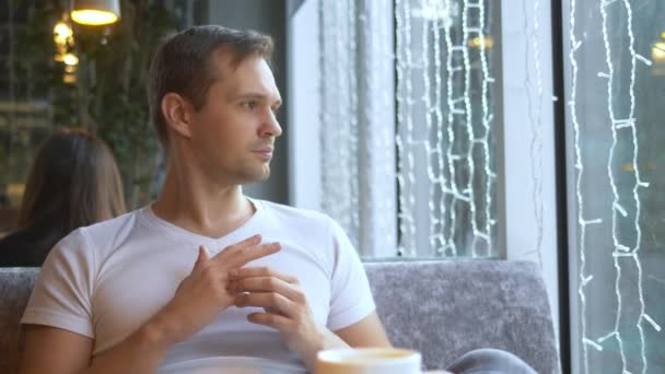 Mann zieht Ehering aus, während er in einem Café sitzt umgeben von Mädchen — Stockvideo