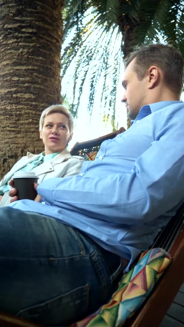垂直。男人和女人在棕榈树下的咖啡店喝咖啡 — 图库视频影像