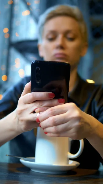 Senkrechtschuss. eine Frau zieht ihren Ehering aus, liest die Nachricht am Telefon vor — Stockfoto