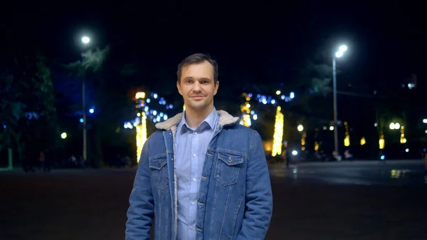 Schöner Mann in der Jacke auf einer Straße in der Stadt bei Nacht, der in die Kamera schaut — Stockfoto