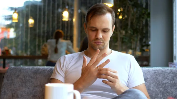 Homme enlève une alliance alors qu'il est assis dans un café. entouré de filles — Photo