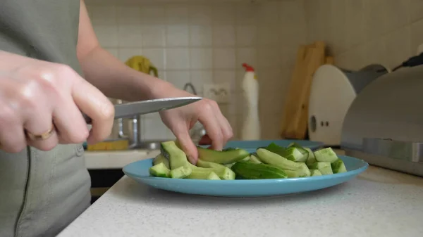 Närbild händer kvinna skära gurka i remsor i köket — Stockfoto