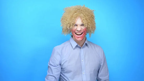 A man with makeup and a wig rubs his face with blood, shows, laughing — Stock Photo, Image