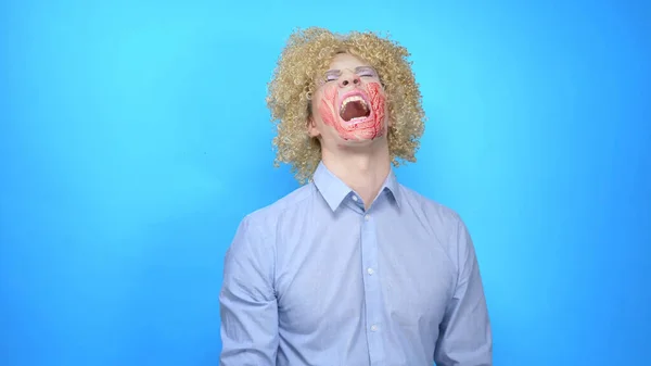 Mężczyzna z makijażem i peruką pociera twarz krwią, pokazuje, śmieje się — Zdjęcie stockowe