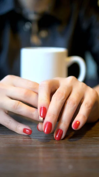 Függőleges lövés. Közelről. A nő leveszi a jegygyűrűjét egy kávézóban ülve. — Stock Fotó