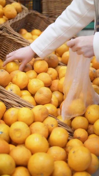 Vertical shot. closeup. woman picks tangerines in a supermarket — Stock Photo, Image