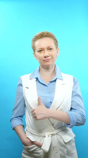 Senkrechtschuss. Blonde Frau ohne Make-up auf blauem Hintergrund. Zeichen super — Stockfoto