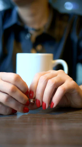 Tiro vertical. Fechar. a mulher tira seu anel de casamento sentado em um café — Fotografia de Stock