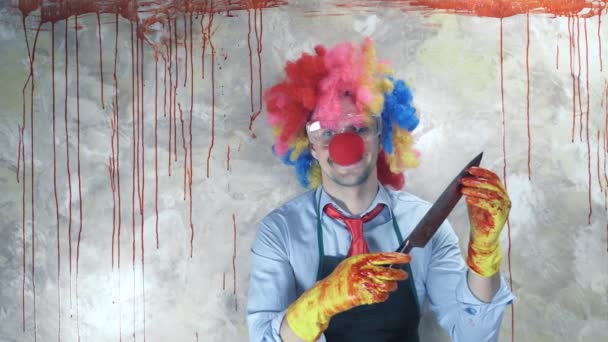 De man in het clownspak op de achtergrond van de bloedige muur met een mes — Stockvideo