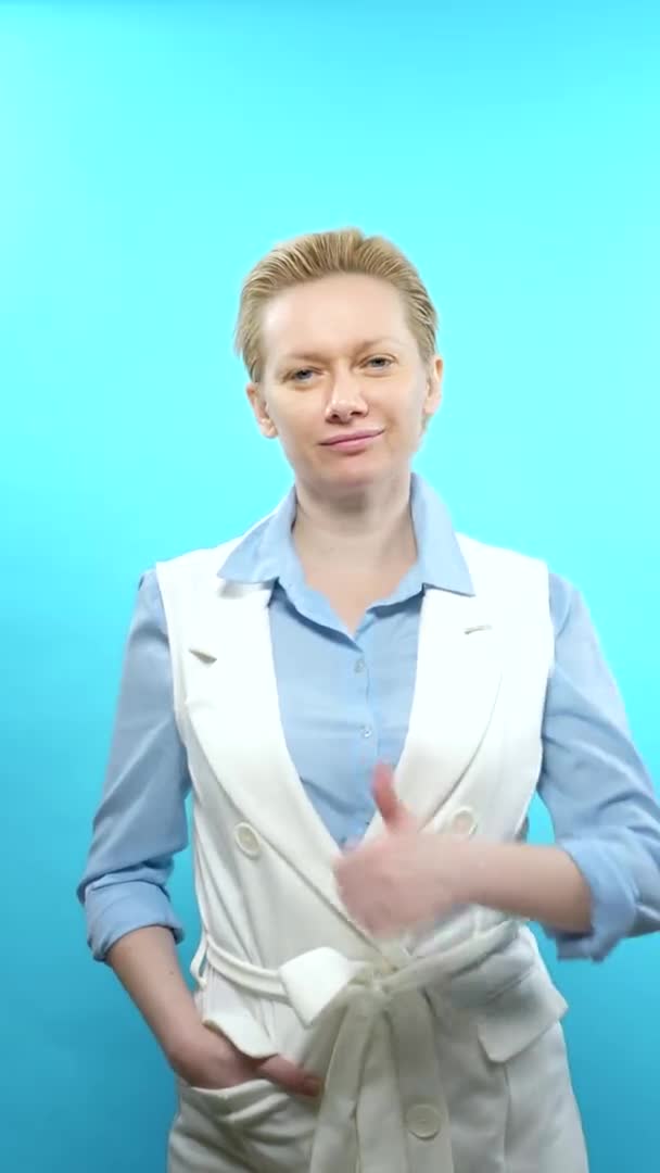Vertikalt skott. blond kvinna utan makeup på en blå bakgrund. tecken super — Stockvideo
