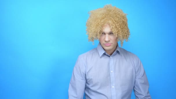 Homem com maquiagem e uma peruca em um fundo azul. espaço de cópia — Vídeo de Stock