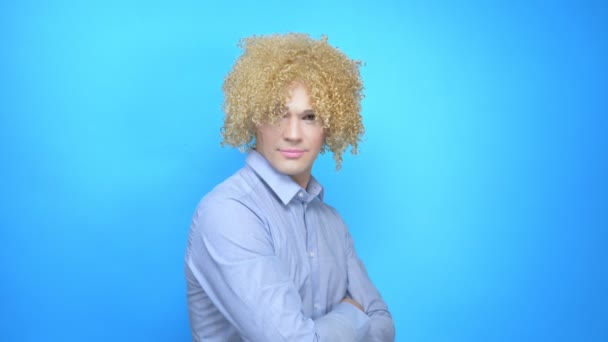 Homem com maquiagem e uma peruca em um fundo azul. espaço de cópia — Vídeo de Stock