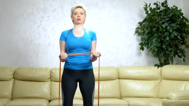 У женщины есть домашний спорт с помощью ленты. силовые тренировки, аэробные упражнения — стоковое видео