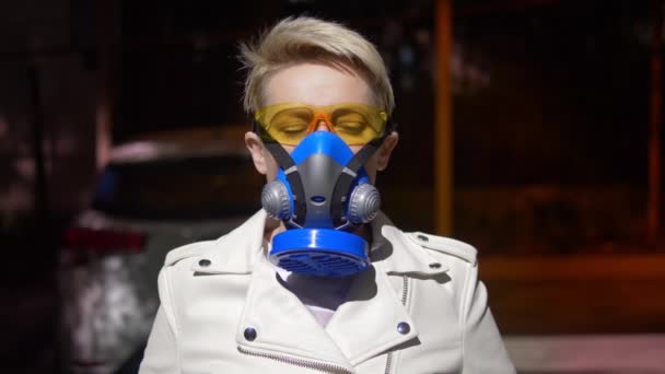 A woman with short hair a respirator outdoors. closeup — Stock Video