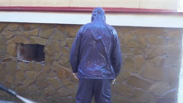 Person in protective suit and respirator is poured from the pressure washer — Stock Video