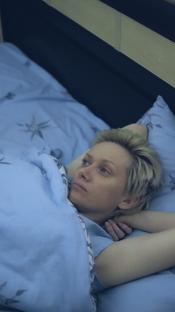 垂直。一位失眠的妇女躺在床上，躺在黑暗中 — 图库视频影像