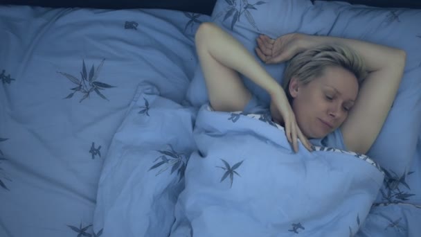 Een vrouw die lijdt aan slapeloosheid ligt in bed in het donker met haar ogen open. — Stockvideo