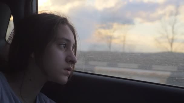 女の子は疲れて移動車の窓から外を見る。車の旅 — ストック動画