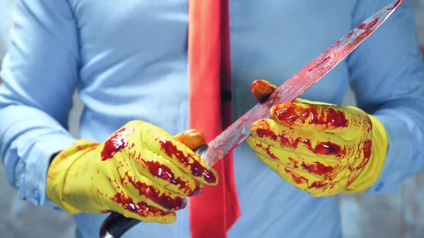 Fechar. mãos masculinas em luvas de borracha segurando uma faca sangrenta — Fotografia de Stock