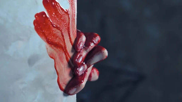 Крупный план. Кровавые руки жертвы держатся за край угла — стоковое фото