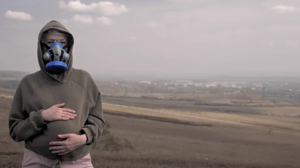 Eine schwangere Frau mit Atemschutzmaske im Freien. Umweltprobleme, Pandemie — Stockfoto