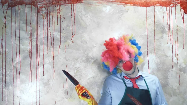 The man in the clown suit in the background of the bloody wall with a knife — Stock Photo, Image