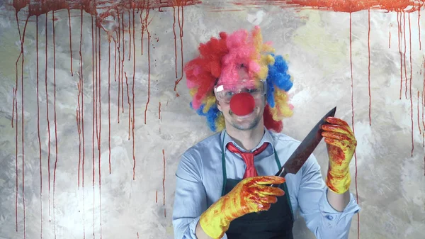 Mężczyzna w kostiumie klauna w tle krwawej ściany z nożem — Zdjęcie stockowe