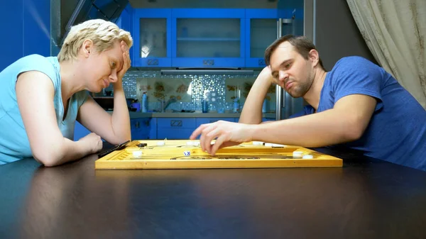 Man en vrouw spelen backgammon in de keuken. familie vrije tijd — Stockfoto