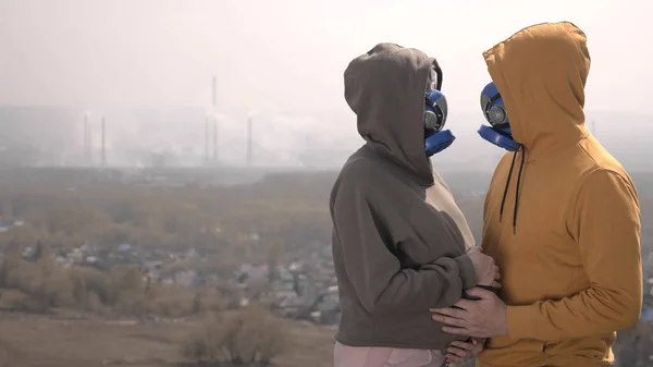 Wanita hamil dan laki-laki dalam respirator di jalan terhadap pipa pabrik — Stok Foto