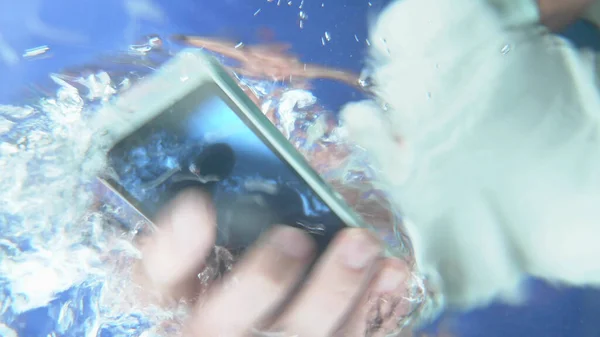 Расплывчатый фон. Человек уронил телефон в воду и вытащил его. . — стоковое фото