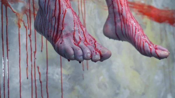 Yakın plan. Kanlı bir duvarın arkasında asılı bir adamın kanlı bacakları. — Stok fotoğraf