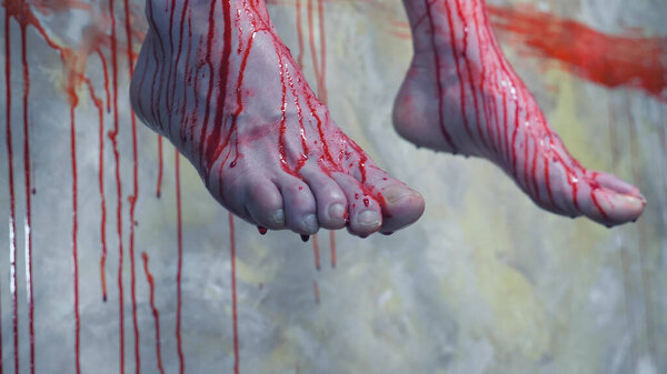 closeup. bloodied legs of a man hanging in the background of a bloodied wall