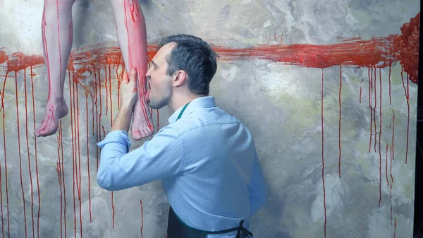 Man with a knife on the background of the bloody walls and the hanging legs — Stock Photo, Image