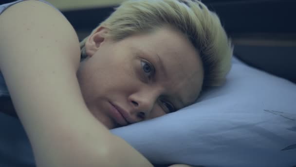 Eine an Schlaflosigkeit leidende Frau liegt mit offenen Augen im Bett. — Stockvideo
