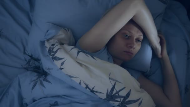 不眠症の女性が目を開けて暗闇の中のベッドに横たわっています. — ストック動画