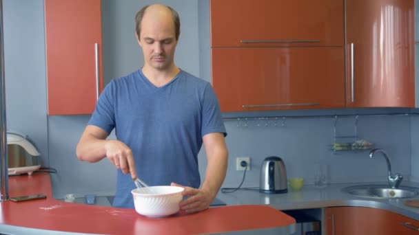 Un hombre calvo con bigote está preparando el postre en la cocina en casa — Vídeo de stock