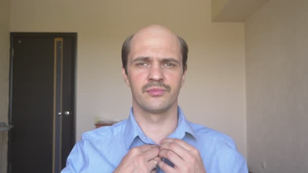 Πορτρέτο. φαλακρός άντρας με μουστάκι κουμπώνει το πουκάμισό του στο σπίτι — Αρχείο Βίντεο
