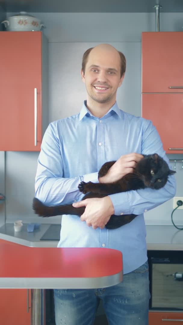 Verticalmente. Retrato. solitário careca homem em uma camisa com um gato em casa — Vídeo de Stock