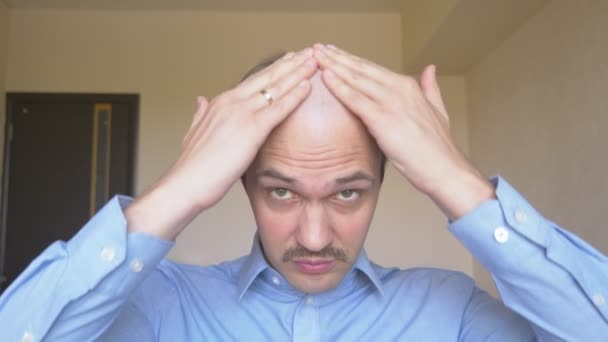 Ein junger Mann mit Glatze reibt sich ein Medikament gegen Haarwuchs in die Kopfhaut. — Stockvideo