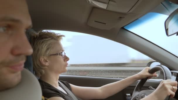 Mujer con gafas mientras conduce un coche, el hombre en el asiento del pasajero — Vídeo de stock