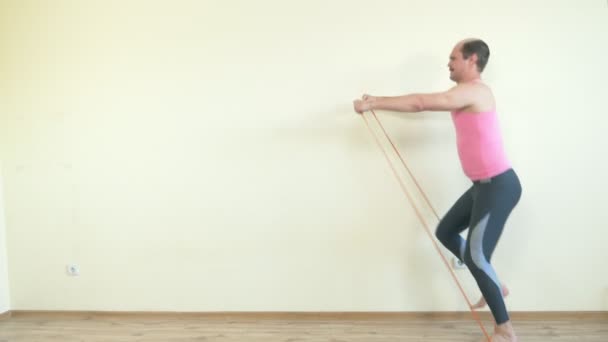 Calvo bell'uomo fa fitness con un elastico. piena altezza. copia spazio — Video Stock