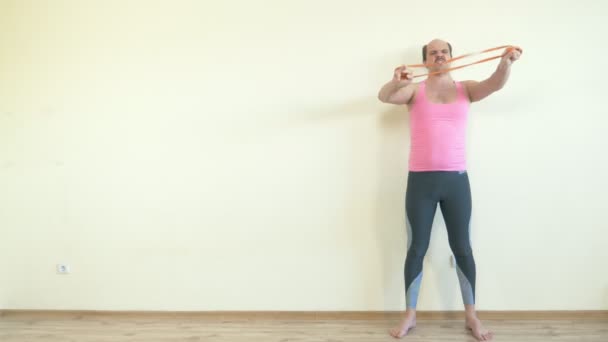 Balding handsome man does fitness with an elastic band. full height. copy space — Stock Video