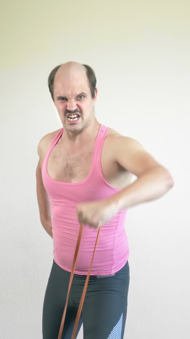 Pionowo. średni strzał, łysy przystojny mężczyzna robi fitness z elastyczny pasek — Wideo stockowe