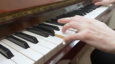 Yakın plan. Kadın elleri usta bir şekilde piyanoda arpeggio çalar.