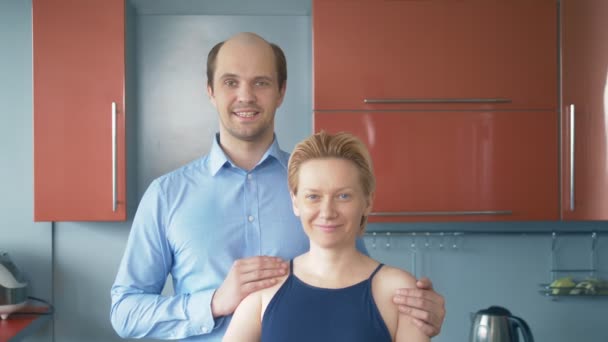 Портрет. муж и жена смотрят в камеру, стоя на кухне — стоковое видео