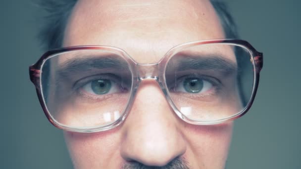Κοντινό πλάνο. Ο καραφλός με μουστάκι άντρας με γυαλιά κοιτάζει την κάμερα με περιέργεια. — Αρχείο Βίντεο