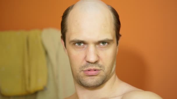 Den skalliga narcissistiske mannen ser sig i spegeln i badrummet. närbild — Stockvideo