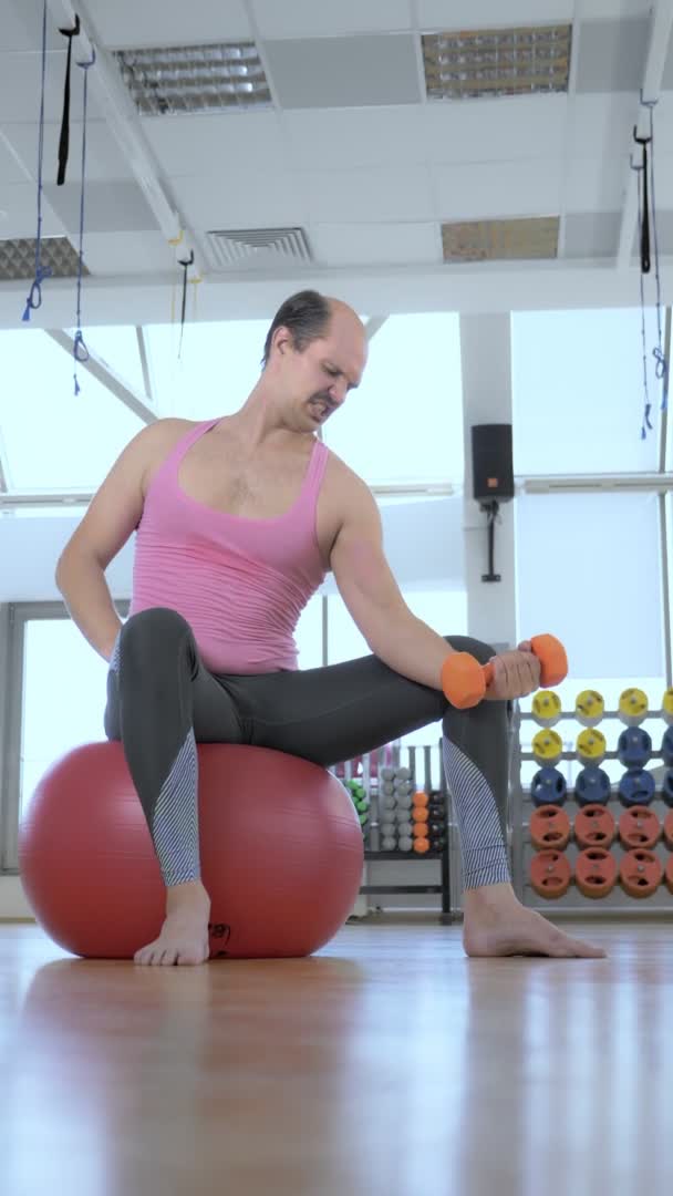Vertikální, plný růst. Plešatý muž trénuje s činkami v tělocvičně. — Stock video