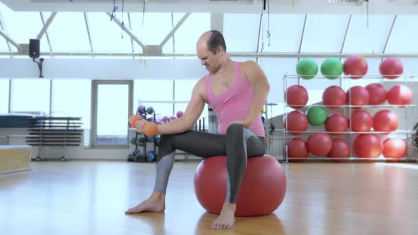 Fuld højde. Skaldet sjov mand træner med håndvægte i gymnastiksalen. – Stock-video